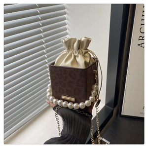 Detail der Leopardenmuster-Minibox-Tasche mit Perlengriff und beigem Kordelzugbeutel