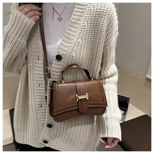 Brown retro crossbody bag with gold metal buckle shown on a knit cardigan