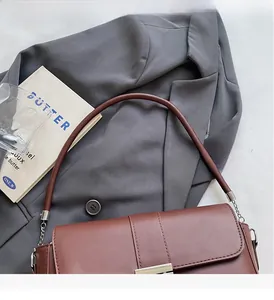 Detail of a brown leather shoulder bag with silver chain links and metal buckle closure