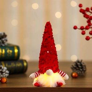 Close-up of glowing Christmas gnome with red sequined hat and warm LED light effect