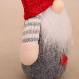 Detail of a handmade plush gnome with red knit hat, white beard, and grey felt body textures