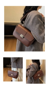 Detail of dark brown leather shoulder bag with silver buckle worn on a grey wool coat