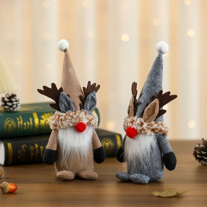 Standing Christmas gnomes with reindeer antlers and white beards on a wooden table