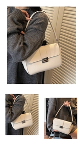 Detail of white leather shoulder bag with silver buckle and chain strap on grey sweater