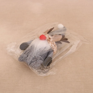 Close-up of a Christmas gnome doll with reindeer antlers in transparent packaging