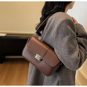 Detail of vintage brown leather crossbody bag with silver rotating clasp and chain strap