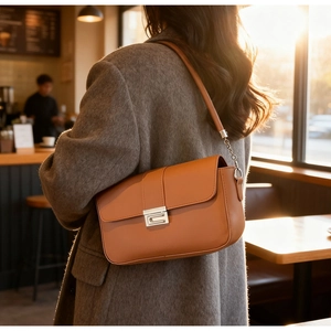 Chic brown leather crossbody bag with silver buckle worn in a cozy cafe setting
