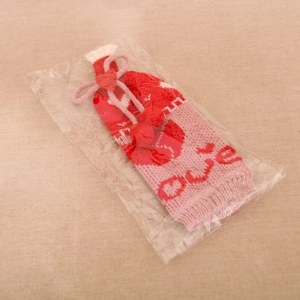 Détail du cache-bouteille tricoté avec lettrage LOVE rouge et pendentif coeur