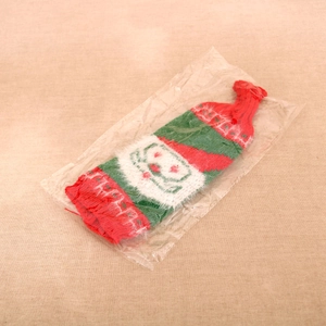 Detail of Christmas knitted wine bottle cover with Santa claus decor in red and white