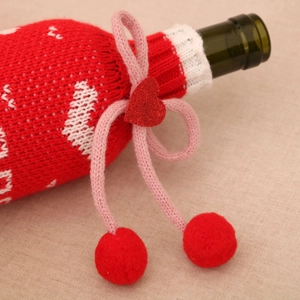 Détail de la housse de bouteille de vin rouge tricotée avec motif flocon et nœud à cœur