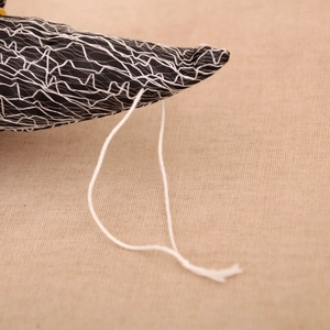Detail of black fabric Halloween decoration with white spiderweb mesh texture and hanging cord
