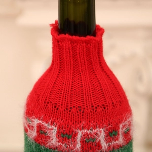 Close-up of a festive knitted Christmas wine bottle cover with red and white wool textures