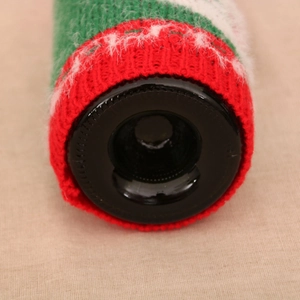 Detail of red and green knitted Christmas wine bottle cover with soft wool texture