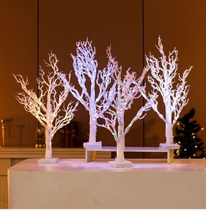 Detail of four white birch-style tabletop trees with multicolor LED lights on white base