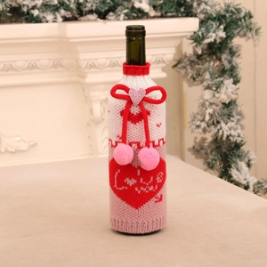 Détail d'un cache-bouteille tricoté avec motif cœur, texte LOVE et pompons roses