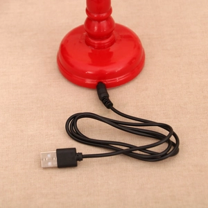 Detail of red musical lantern base with USB power cable on a beige fabric background