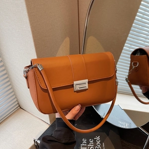 Brown leather crossbody bag with silver buckle and elegant chain strap in a lifestyle setting