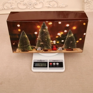 Vista detallada de la caja de regalo del árbol de Navidad en una báscula pesando 470 g