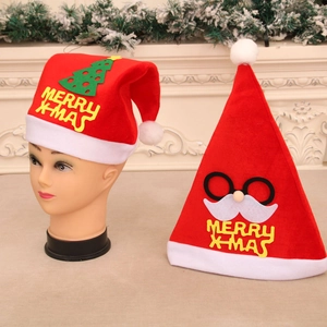 Close-up of red velvet Christmas hats with white pom-poms and Merry X-Mas embroidery