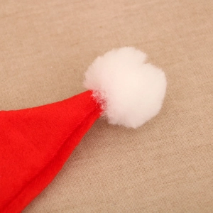 Close-up of a soft red Christmas hat with a fluffy white plush pom-pom detail