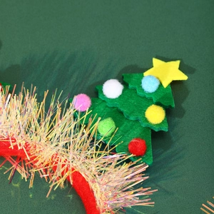 Detailed close-up of green felt Christmas tree headband with colorful pom-poms and tinsel