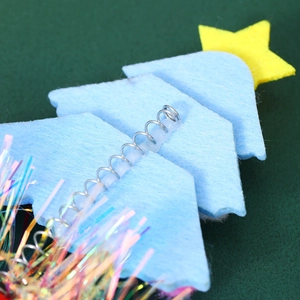 Detail of blue felt Christmas tree headband with yellow star and spring attachment