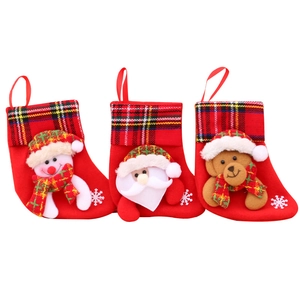 Three Christmas stockings set with Santa, Snowman and Reindeer hanging on festive plaid trim