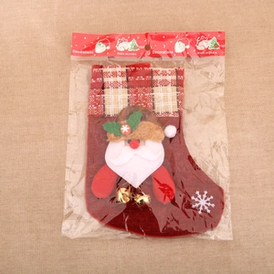 Détail d'une chaussette de Noël en toile rouge avec un Père Noël 3D et une clochette