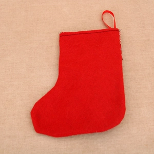 Détail d'une chaussette de Noël en feutre rouge avec boucle de suspension sur jute