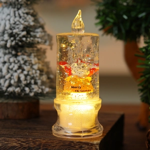 Close-up of LED Christmas candle with floating silver glitter and Santa Claus decor