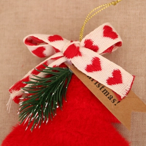 Détail d'un ornement de Noël en peluche rouge avec nœud, aiguilles de pin et étiquette