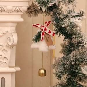 Détail de cloche de Noël en peluche avec nœud rouge et étiquette sur la cheminée