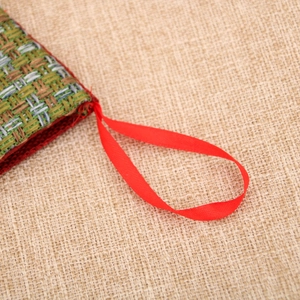 Macro shot of colorful woven fabric texture and red satin hanging loop for Christmas stocking