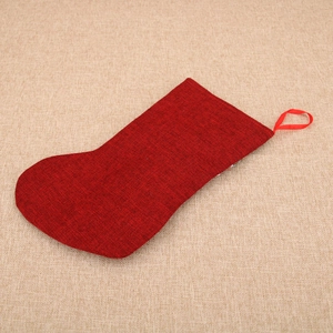 Close-up of red burlap Christmas stocking with a gnome doll and a hanging ribbon