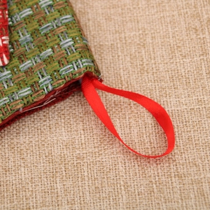 Close-up of woven burlap Christmas stocking texture with red silk hanging loop detail