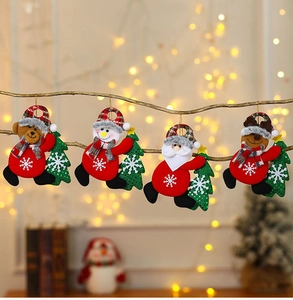 Dettaglio di quattro addobbi natalizi in peluche appesi a un ramo di legno vero