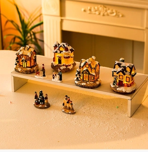 Detailed macro view of four light-up Christmas resin houses with glowing LED windows