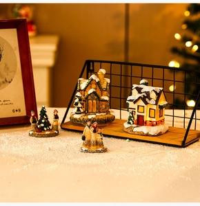 Close-up of glowing resin Christmas village houses with warm LED lights and snow detail