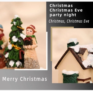 Close-up of hand-painted resin Christmas figurines with girl, tree, and snow-covered cottage