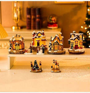 Close-up of lighted miniature Christmas houses and resin figurines with snow details