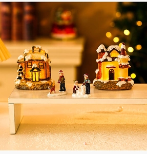 Close-up of lighted resin Christmas village houses and miniature figurines on a shelf