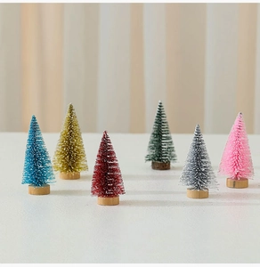Close-up of colorful 10cm mini cedar Christmas trees with snow effect and wooden bases