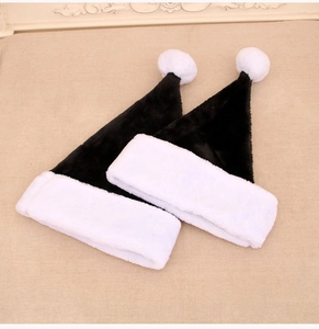 Dettaglio di due cappelli natalizi neri in peluche con bordo bianco e pompon morbido