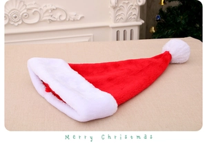 Dettaglio del cappello di Natale nero in peluche spesso con pompon bianco su tavolo