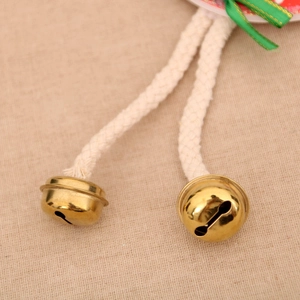 Nahaufnahme goldener Weihnachtsklocken mit weißem Seil und grüner Schleife als Deko