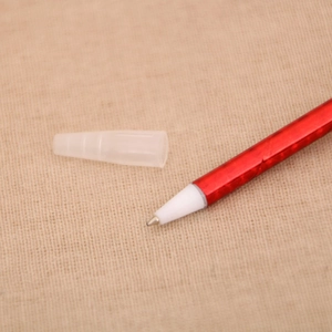 Close-up of red Christmas ballpoint pen tip with transparent cap on textured fabric