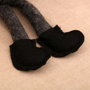 Détail des jambes grises en feutre et bottes noires d'un gnome de Noël assis