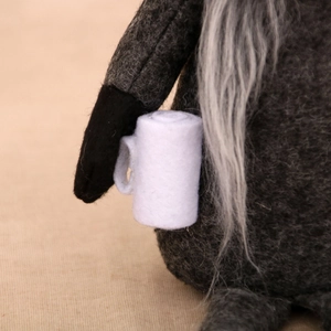 Gros plan d'un nain de Noël gris tricoté avec une tasse en feutre blanc et barbe douce