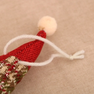 Detail of red knit Christmas ornament with white plush pompom and cotton hanging rope