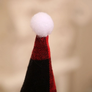 Close-up of a red and black buffalo plaid Christmas hat with a soft white pompom topper